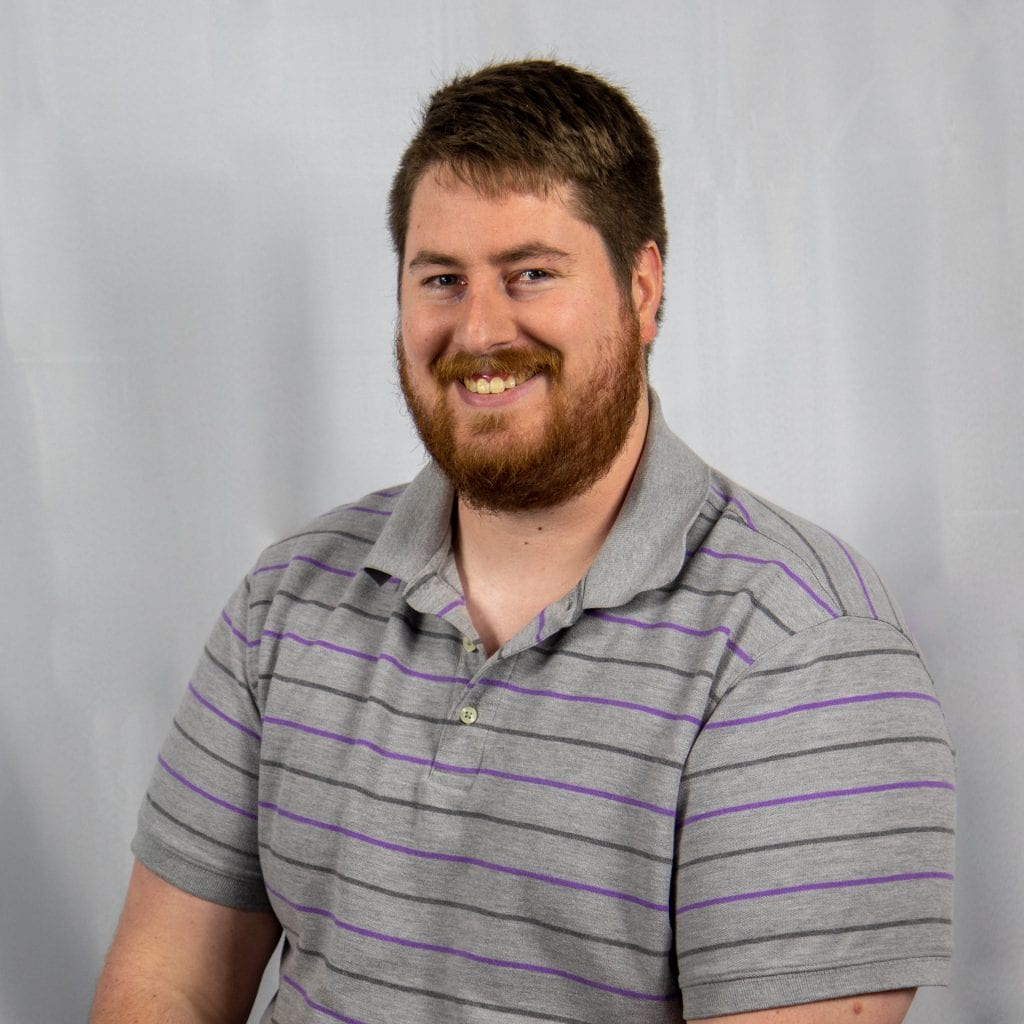 White male with short brown hair, a neatly kept beard wearing a gray polo shirt with horizontal stripes.