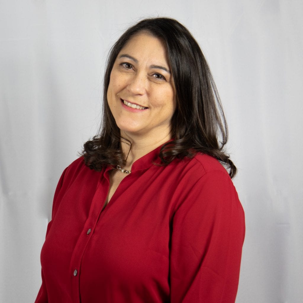 White female with wavy dark hair wearing a red top.
