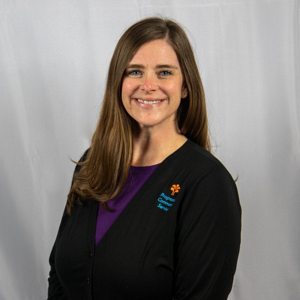 White female with long brown hair wearing a Purple shirt and black sweater
