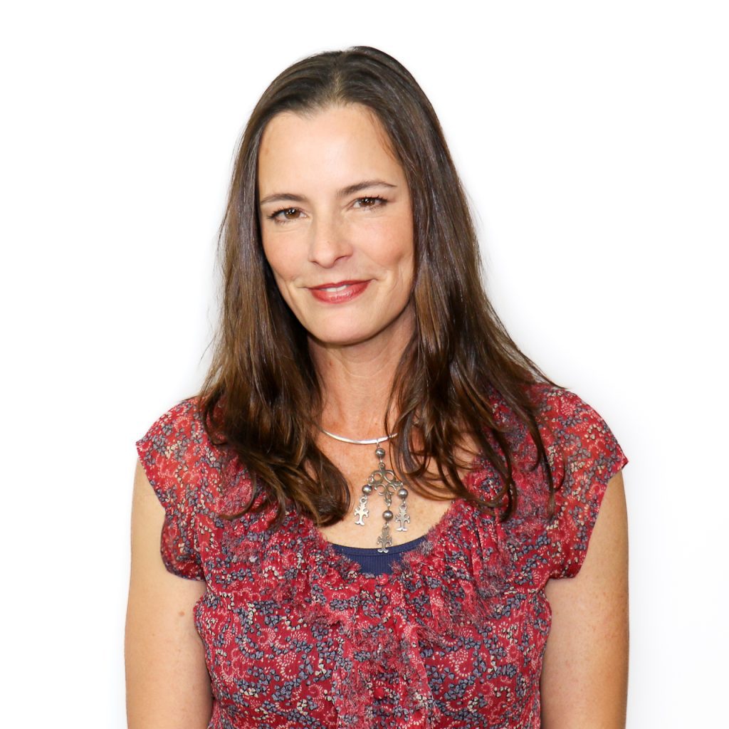 White female with long brown hair wearing a red shirt with blue designs