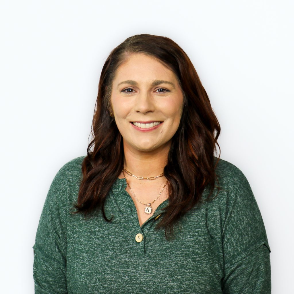 White female with dark wavy hair, wearing a green shirt.