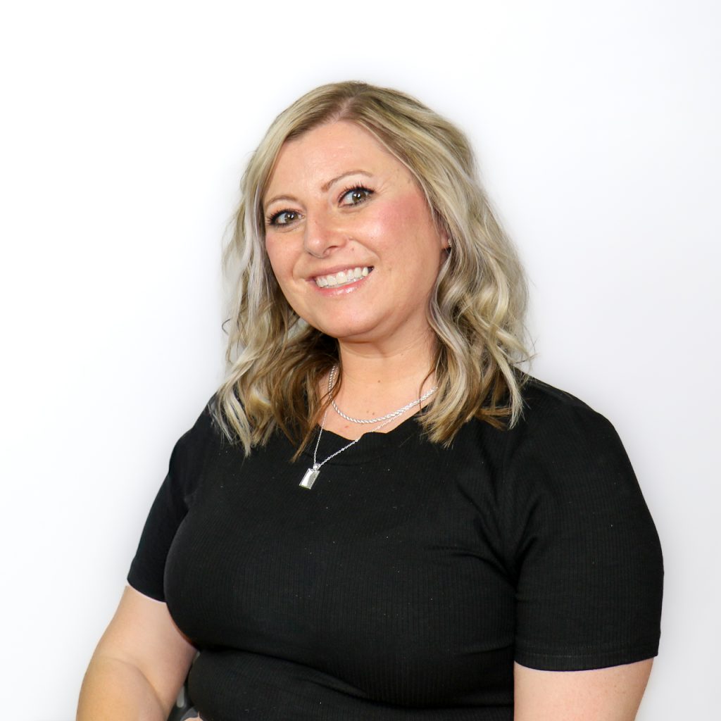 White woman with shoulder length blonde wavy hair and a black shirt.